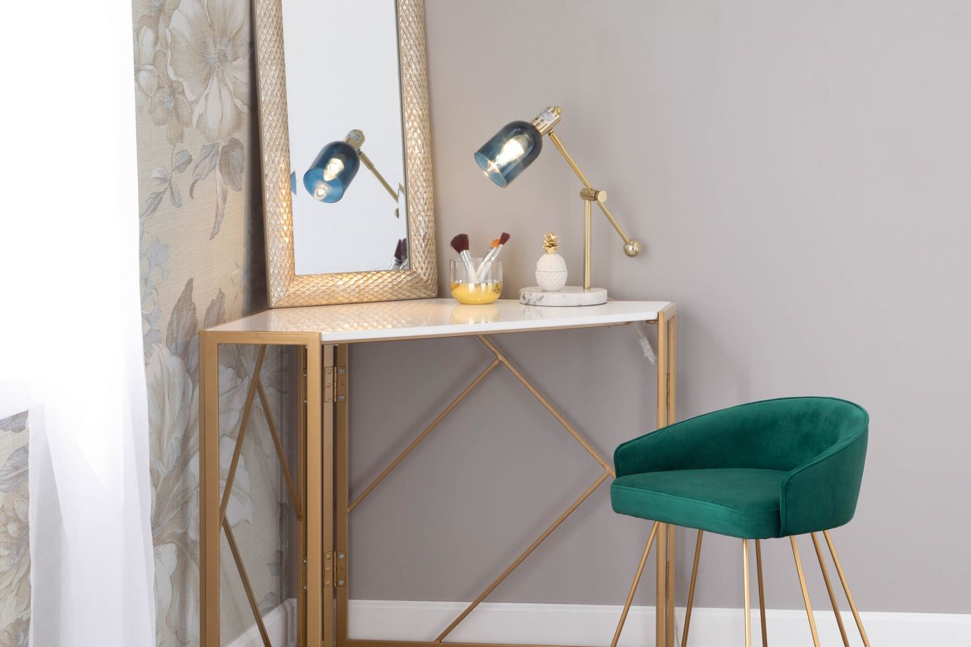 Vanity table with a gold frame, white top, and a green velvet chair.
