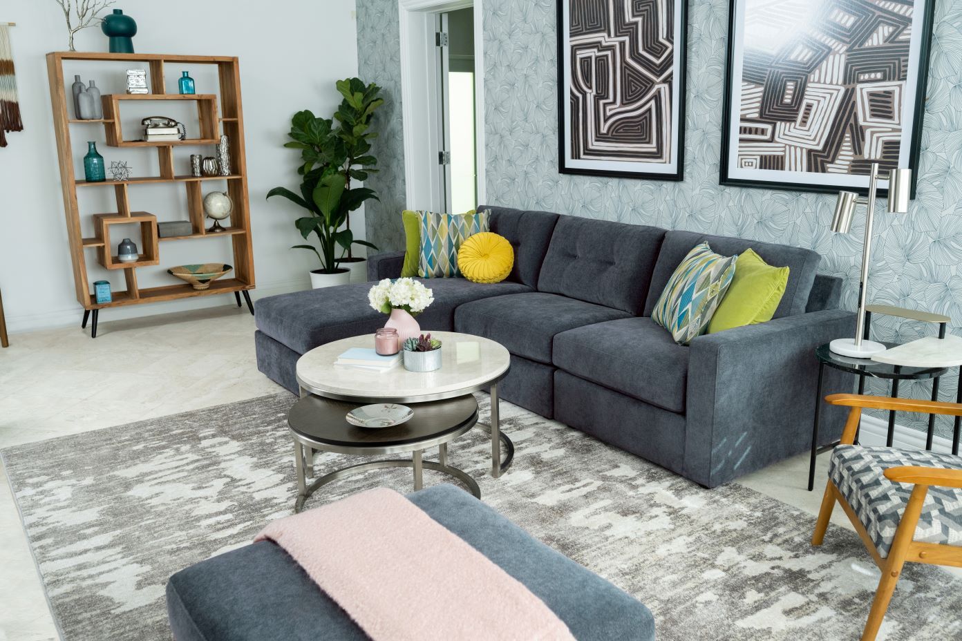 A modern living room with a gray sectional sofa, a patterned rug, and abstract art.
