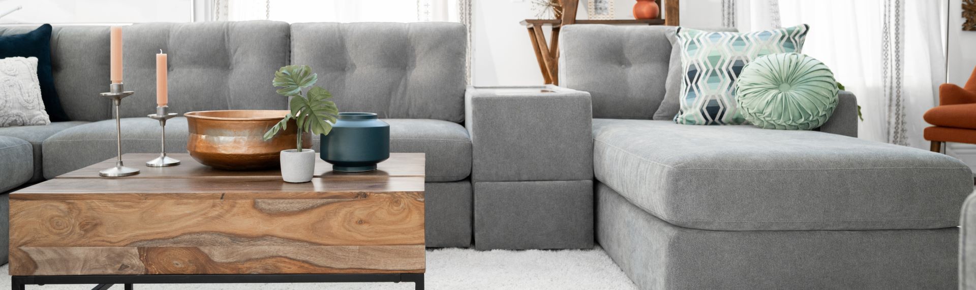 Gray sectional sofa with a wooden coffee table and decorative items.