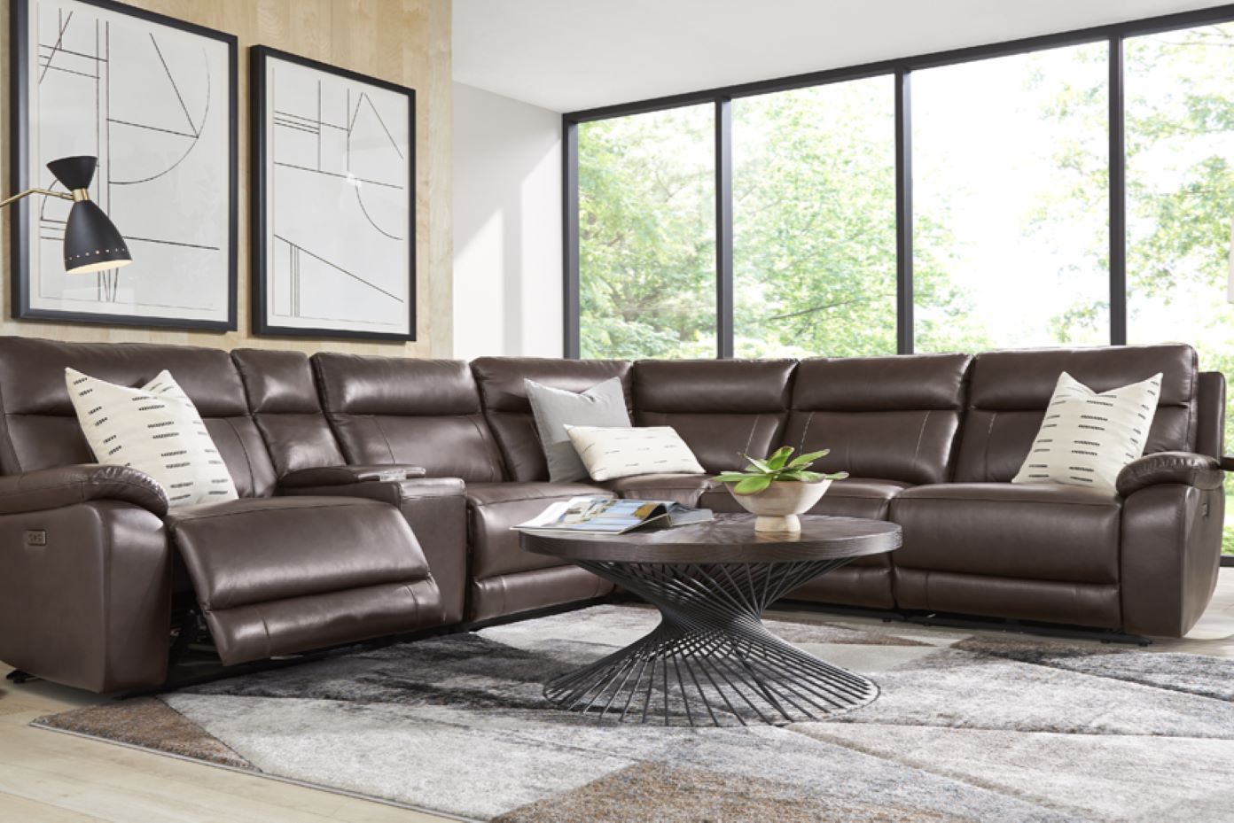 Brown leather sectional sofa with a round coffee table and a patterned rug.
