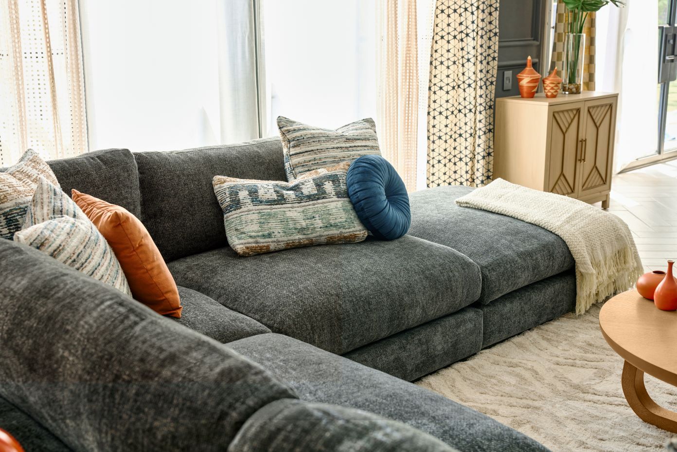 A gray sectional sofa with decorative pillows and a throw blanket.

