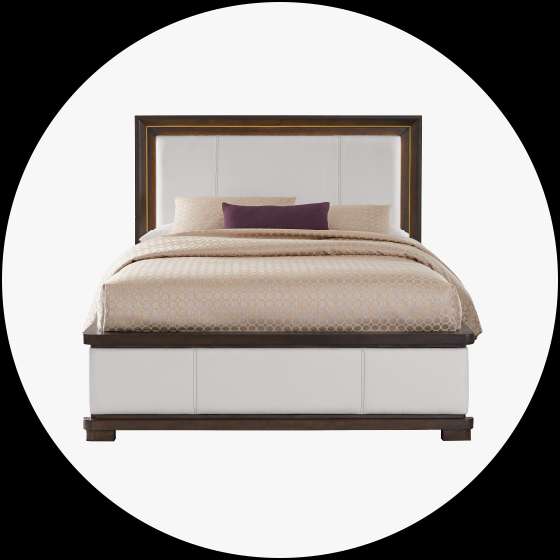 A white and brown bed with a patterned comforter and pillows.
