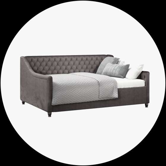 Gray tufted daybed with pillows and a blanket.

