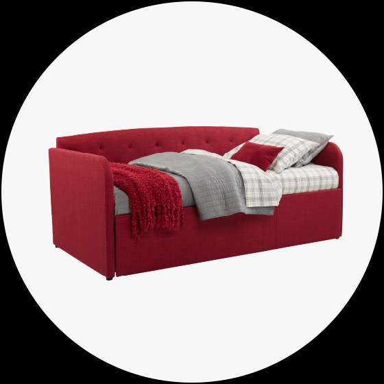 Red upholstered daybed with pillows and blankets.
