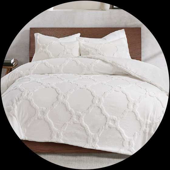 White tufted comforter set on a wooden bed frame.

