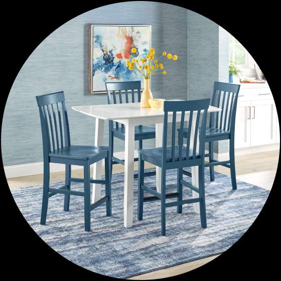 A dining set with a white table and blue chairs on a blue rug.
