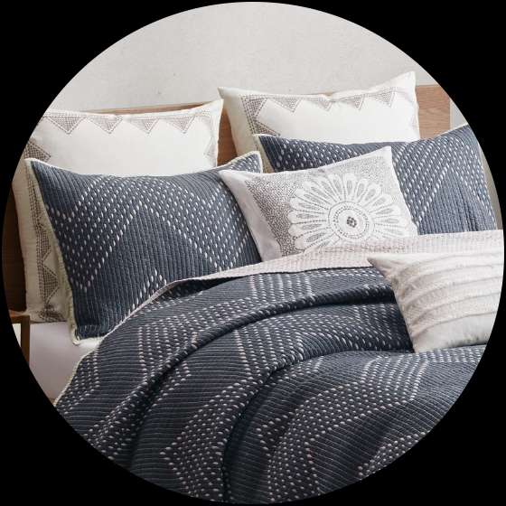 Bedding set with blue patterned quilt and pillows.
