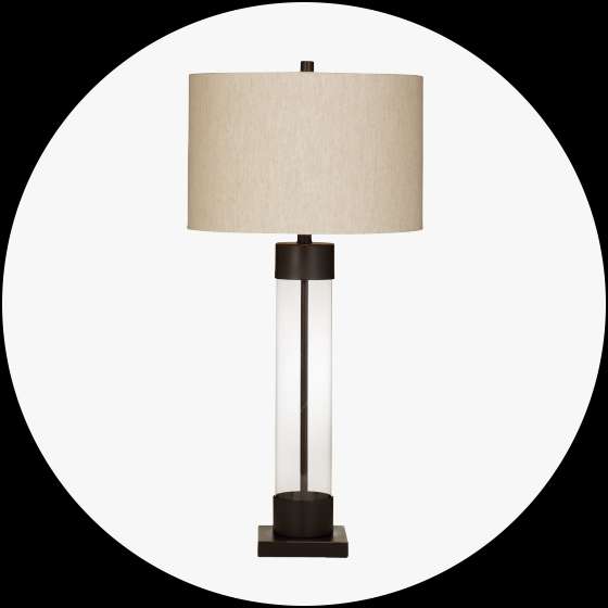 Table lamp with a beige lampshade and a clear glass column base.
