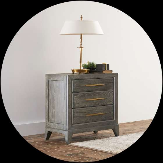Nightstand with three drawers, a lamp, and decorative items.

