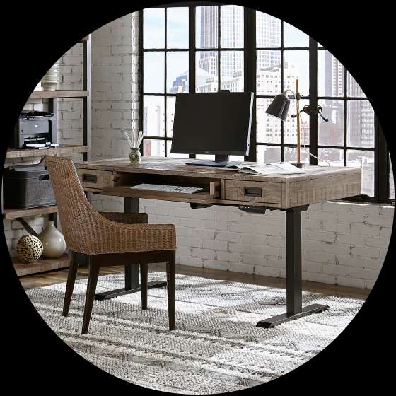 A wooden desk with a computer, lamp, and chair in front of a window.

