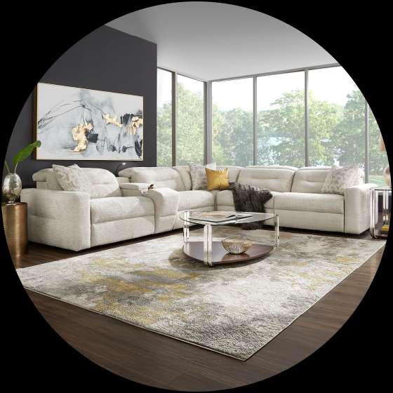 A sectional sofa in a living room with a rug and artwork.

