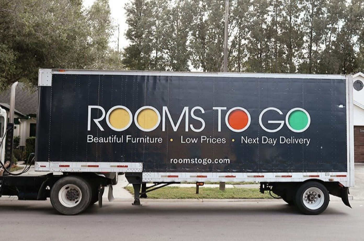 Rooms To Go truck with "Beautiful Furniture, Low Prices, Next Day Delivery" on the side.
