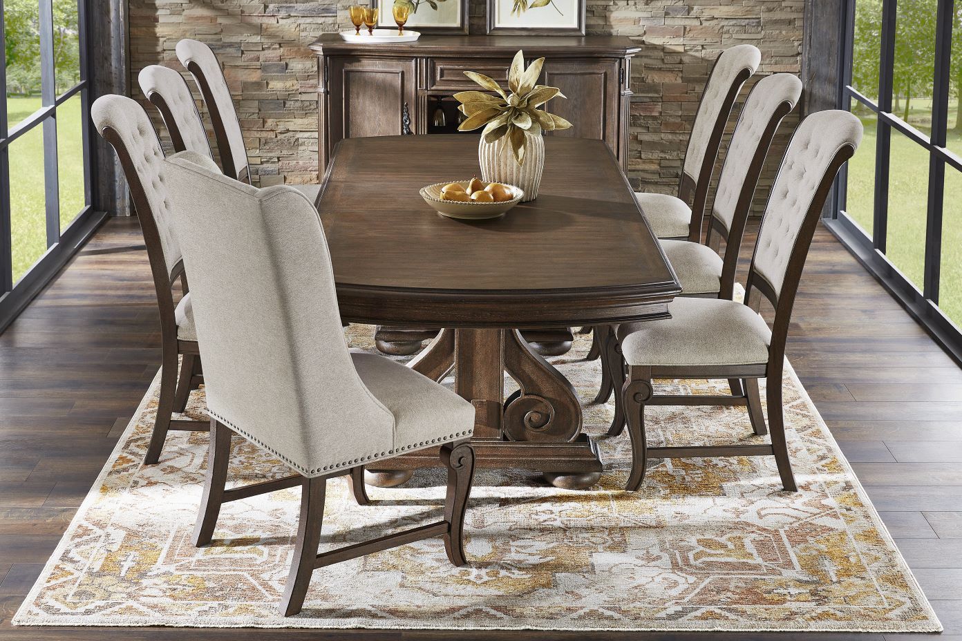 Dining room set with a dark wood table, upholstered chairs, and a patterned rug.
