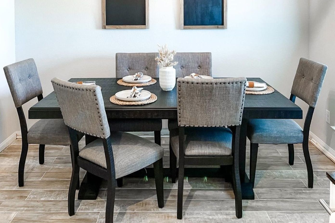 Dining table with six gray upholstered chairs.
