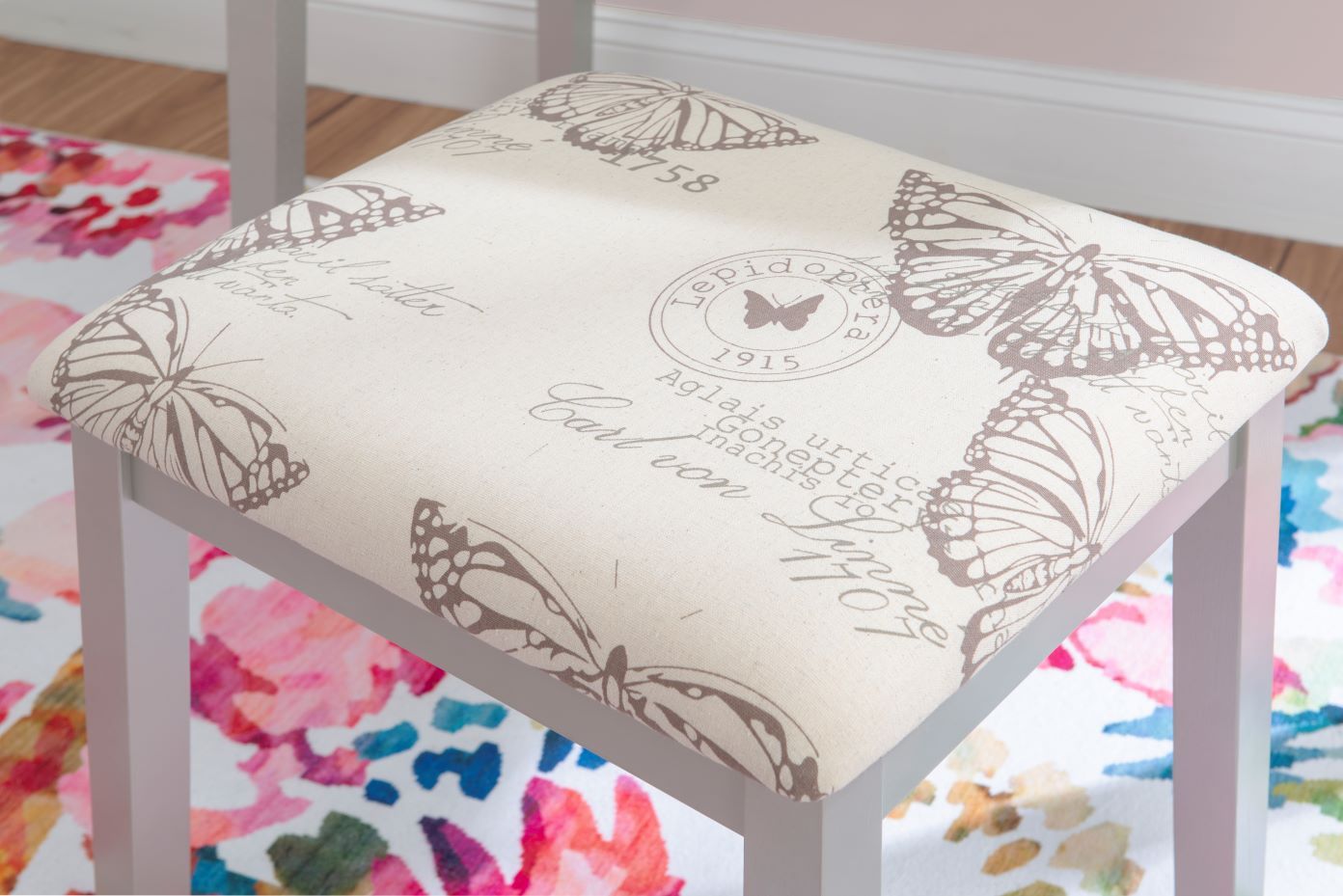A white stool with a butterfly print seat.
