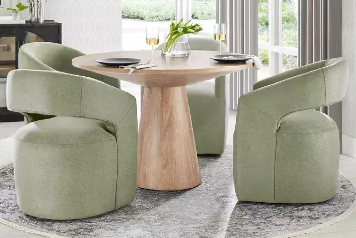 A round dining table with four green chairs.
