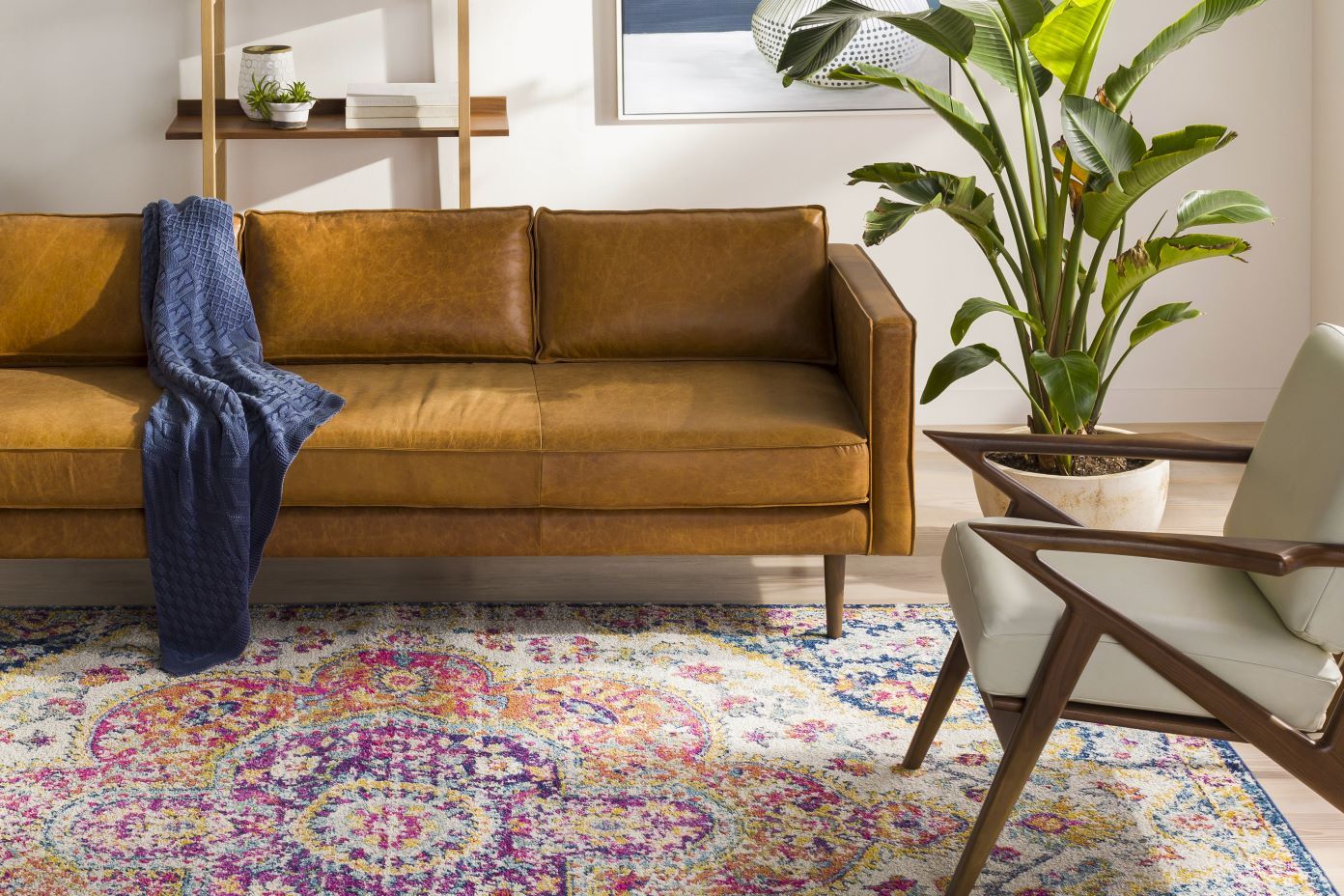 A living room with a brown leather sofa, a patterned rug, and a white chair.
