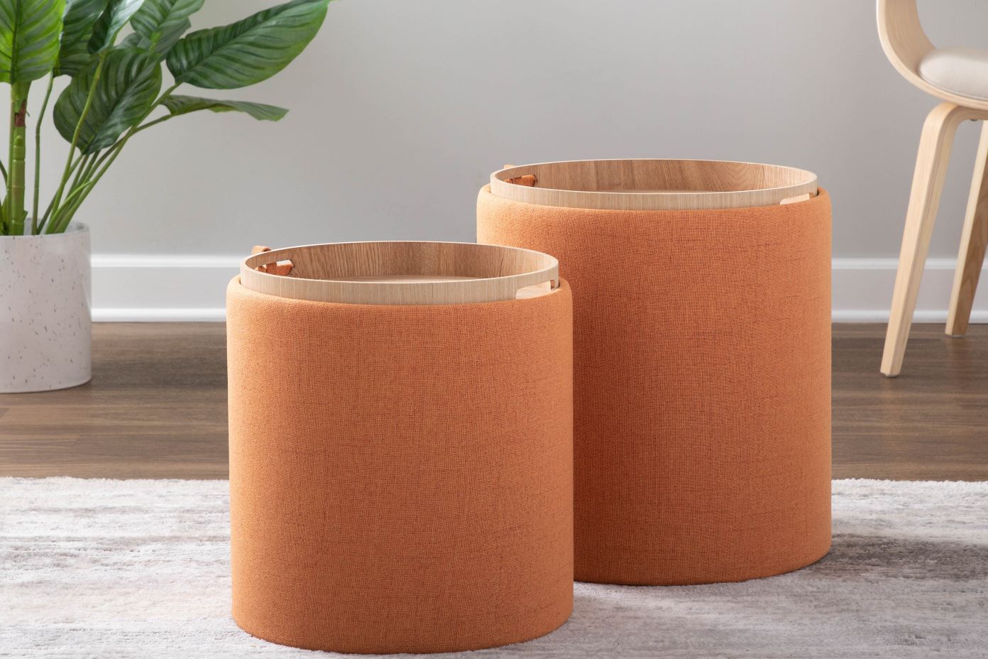 Two orange cylindrical ottomans with wooden tops.
