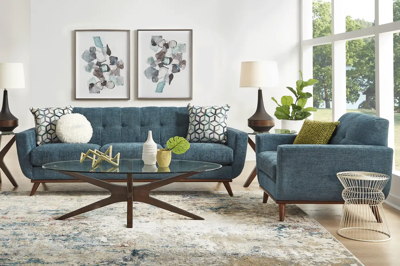 Living room with blue sofa, armchair, and coffee table. Two framed abstract art pieces hang above the sofa.