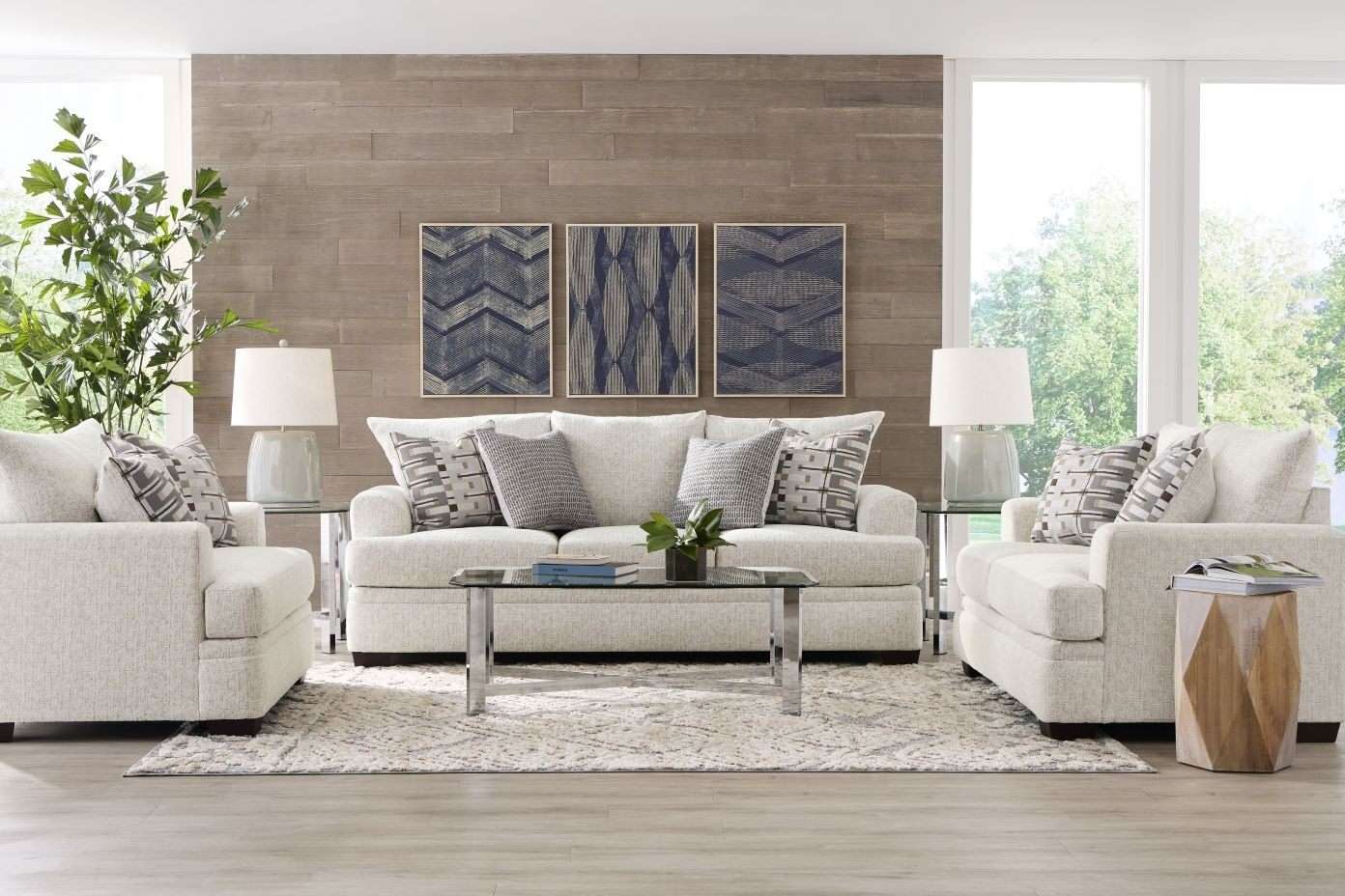 Living room with a white sofa, two armchairs, and a coffee table. Three framed art pieces hang on the wall.