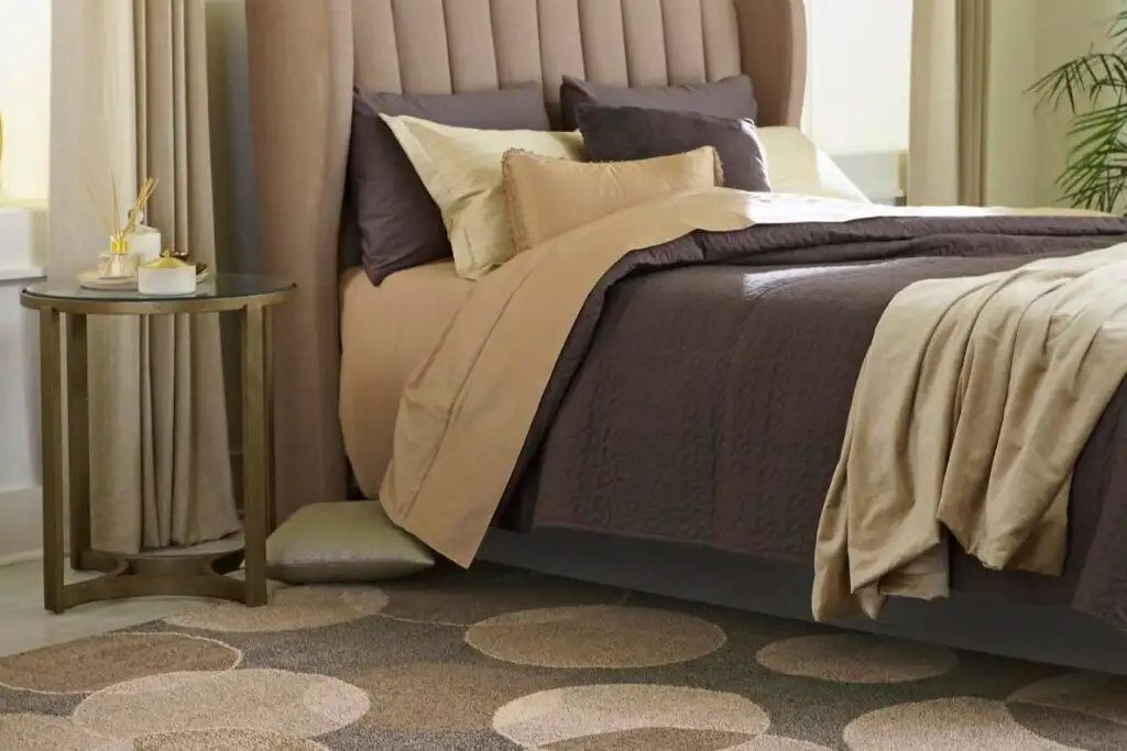 A bed with brown bedding and a patterned rug.
