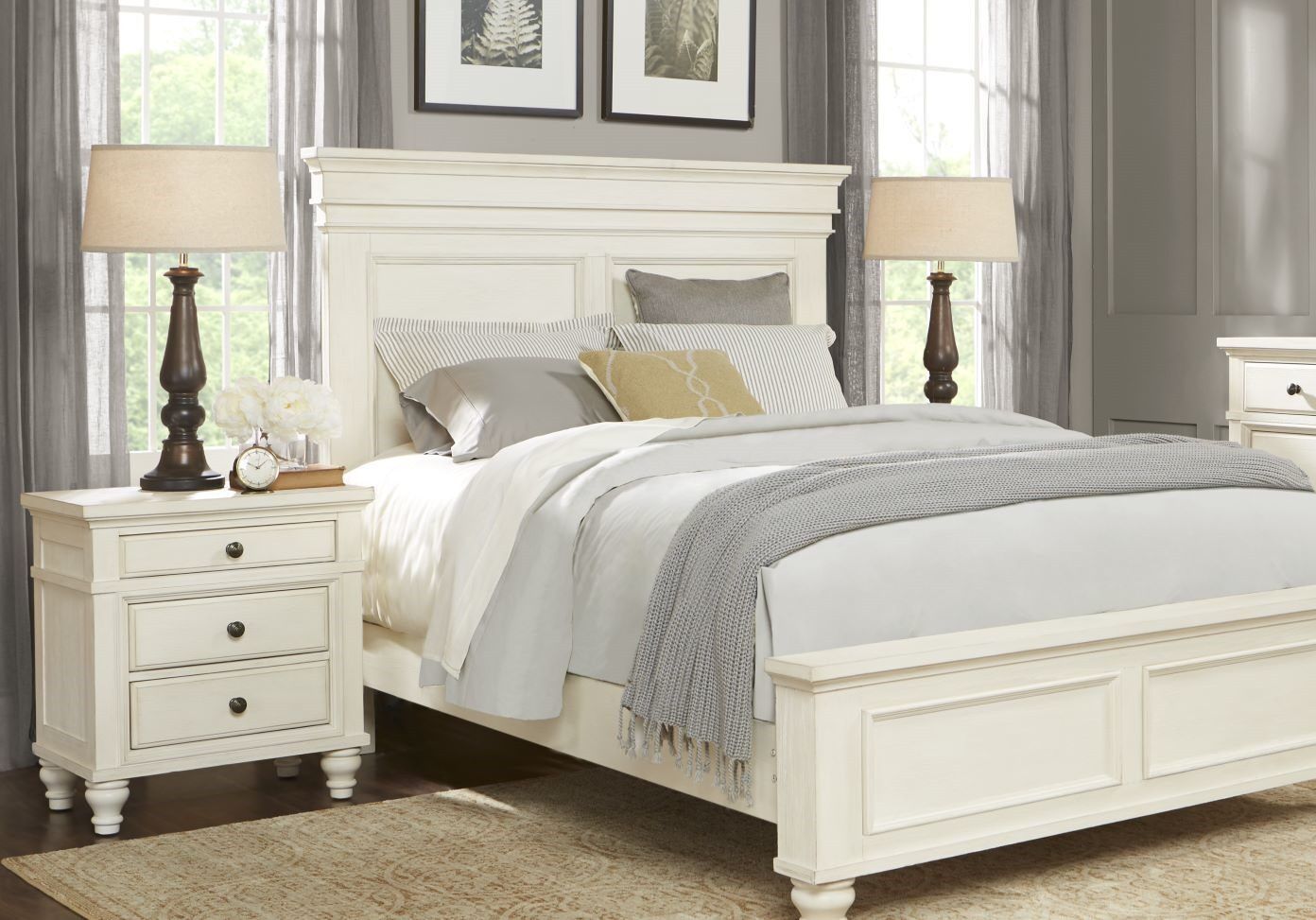 White bedroom set with a bed, nightstands, and lamps.
