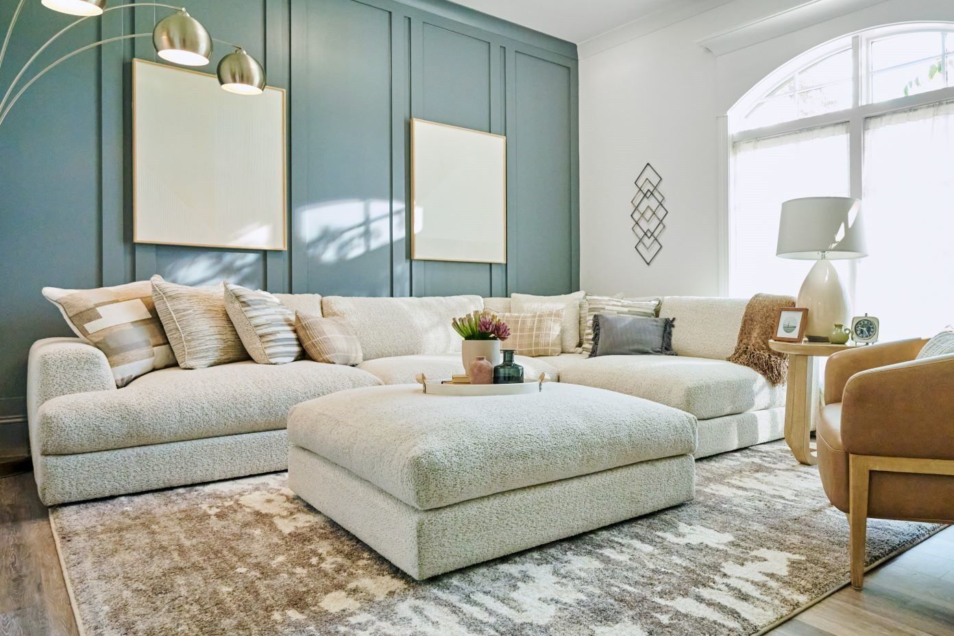 A living room with a large sectional sofa, ottoman, and area rug.
