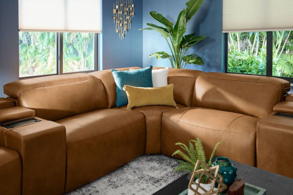 Brown leather sectional sofa with pillows in a living room.
