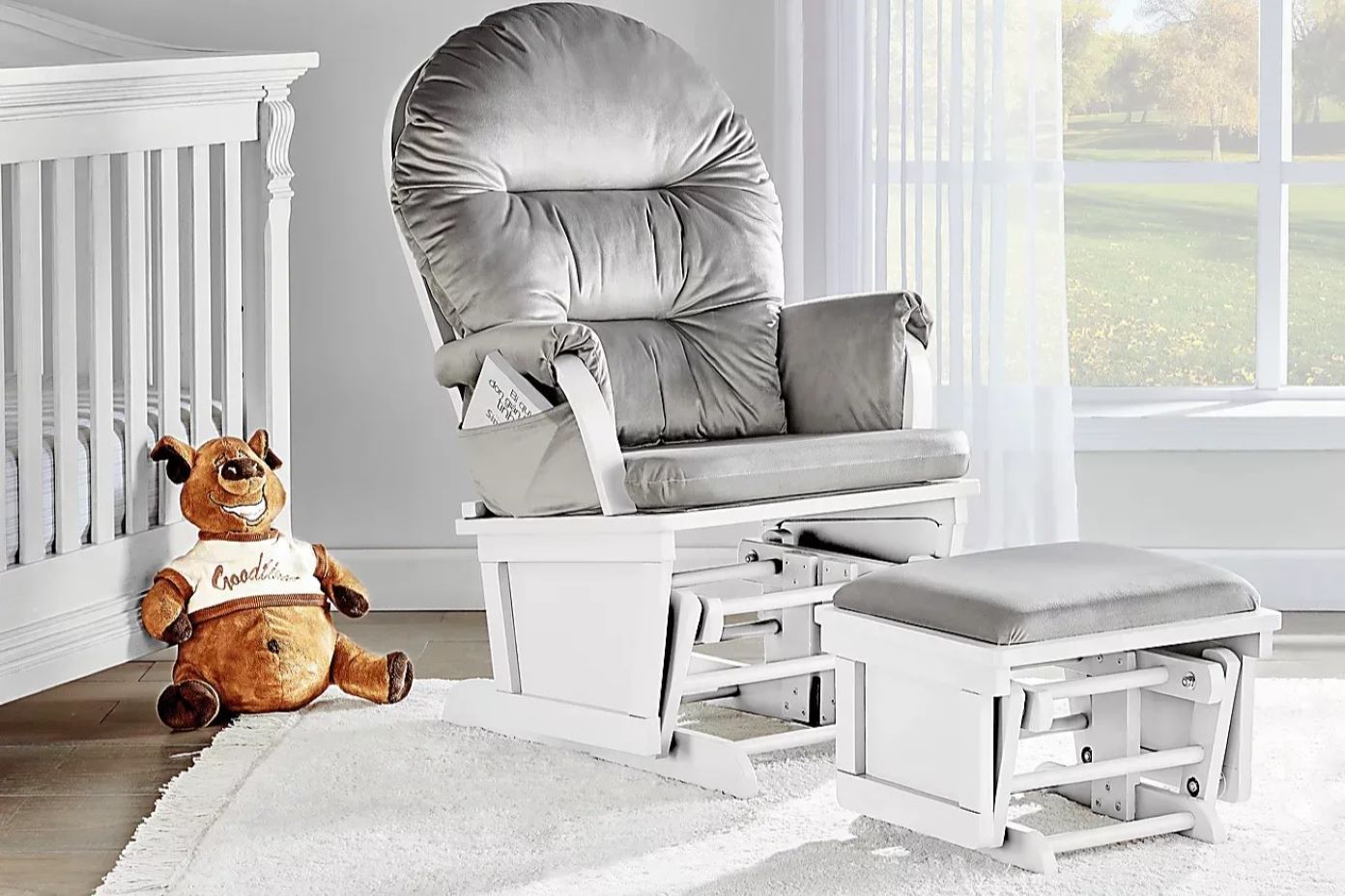 White glider chair with a matching ottoman. A stuffed bear sits on the floor.
