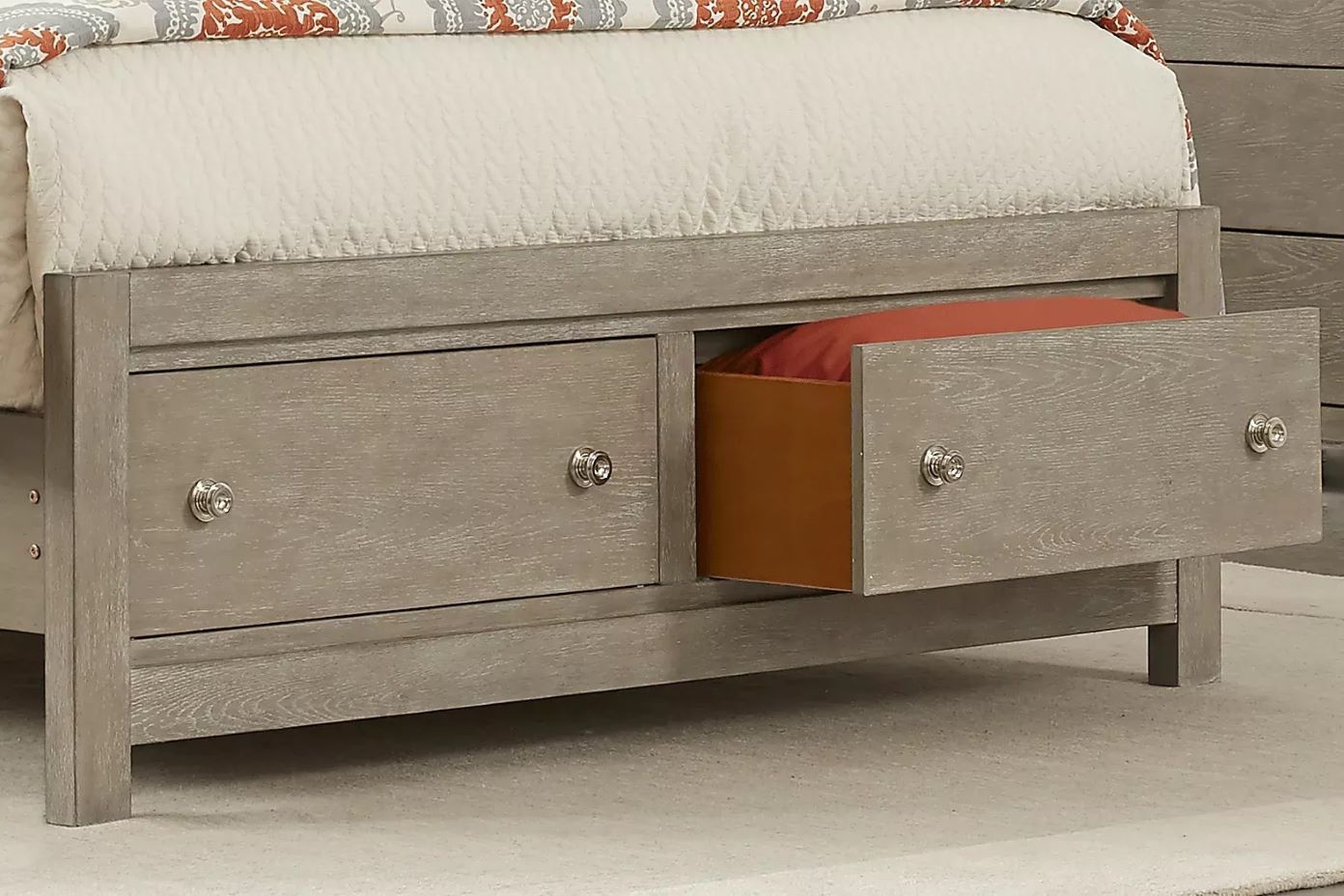 A bed frame with two drawers, one open, revealing a red pillow.
