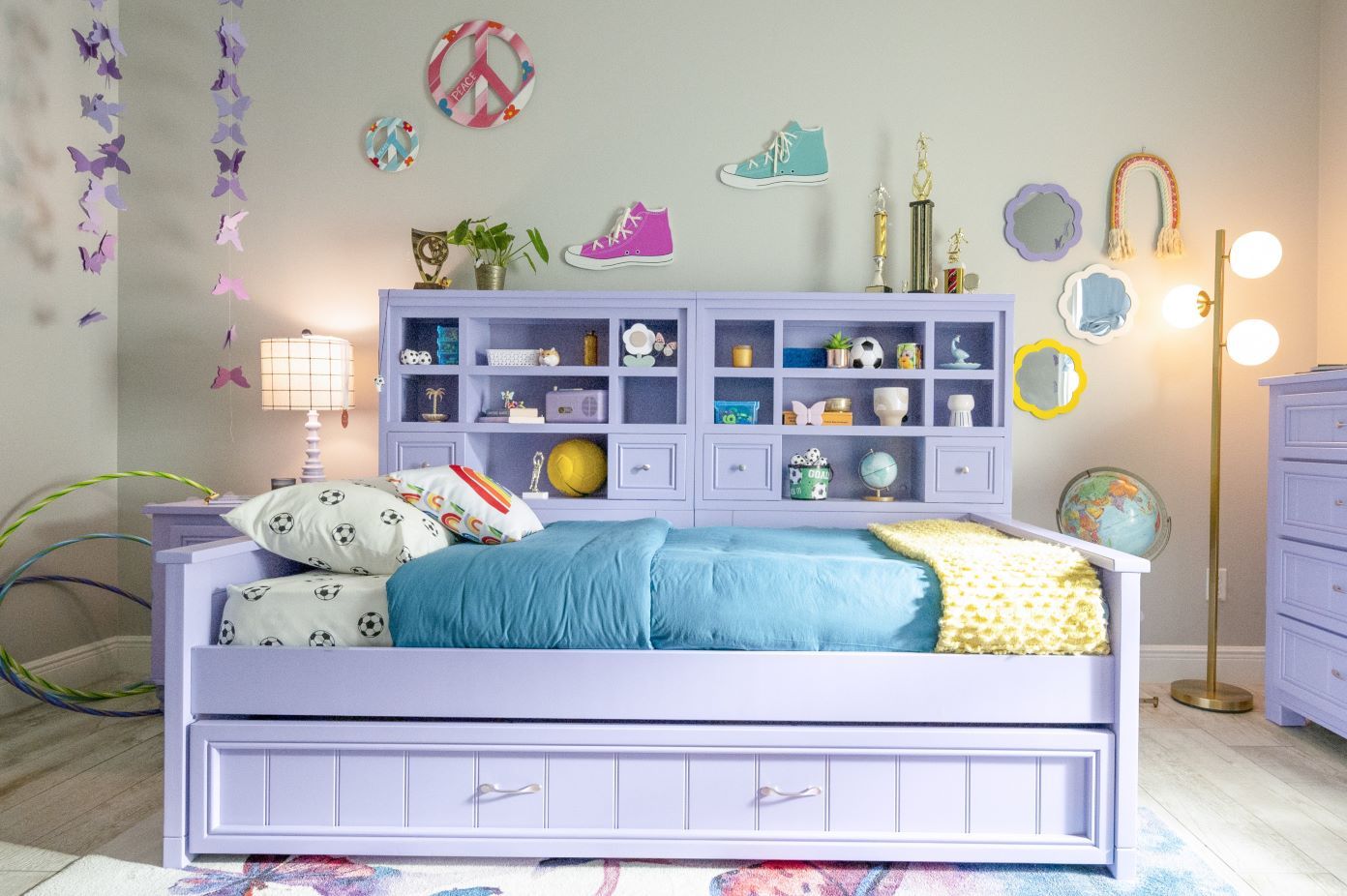 A lavender bed with a headboard, a lamp, and decorative items.
