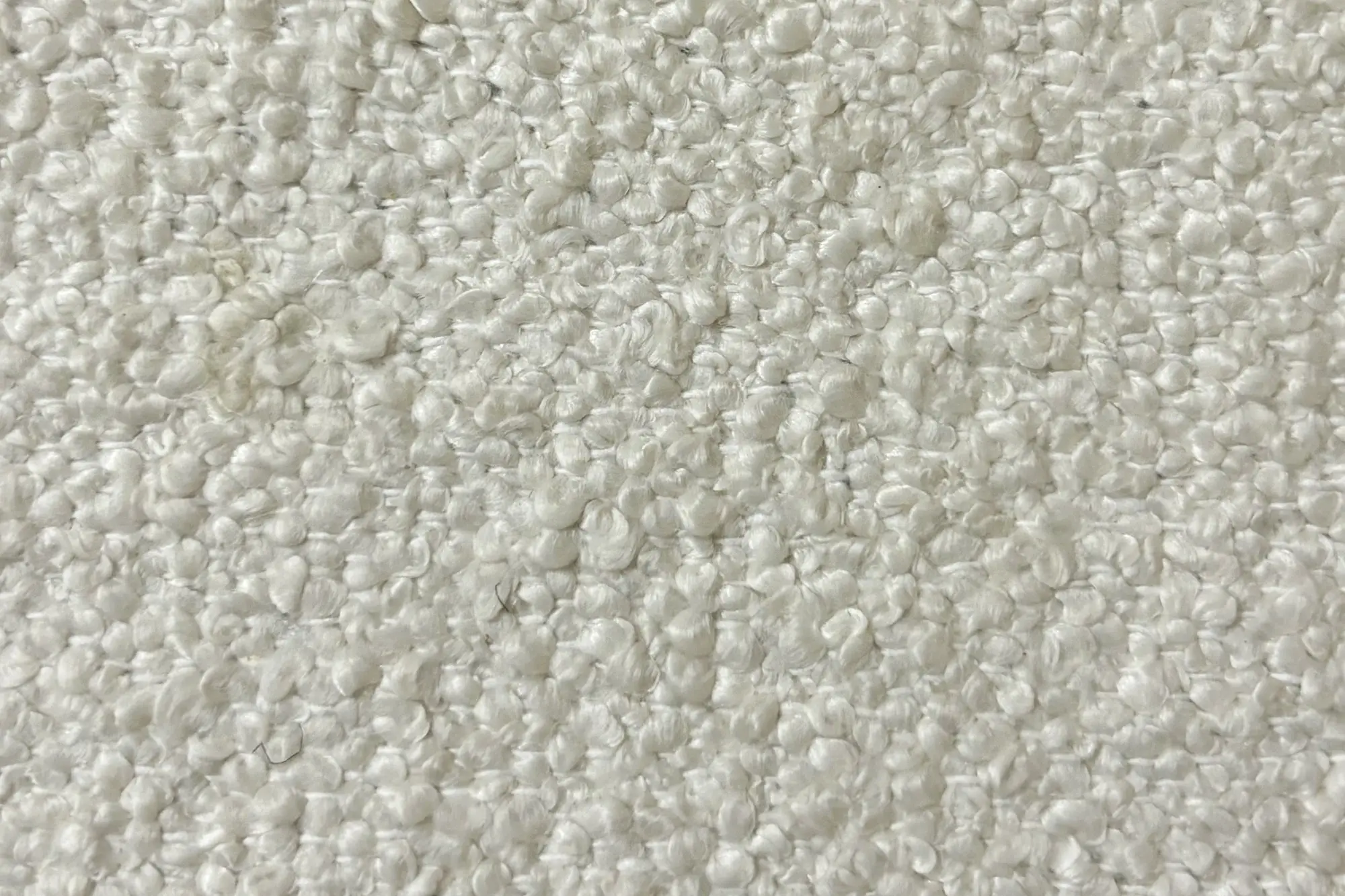 Close-up of a white, textured bouclé fabric with a nubby, looped surface.