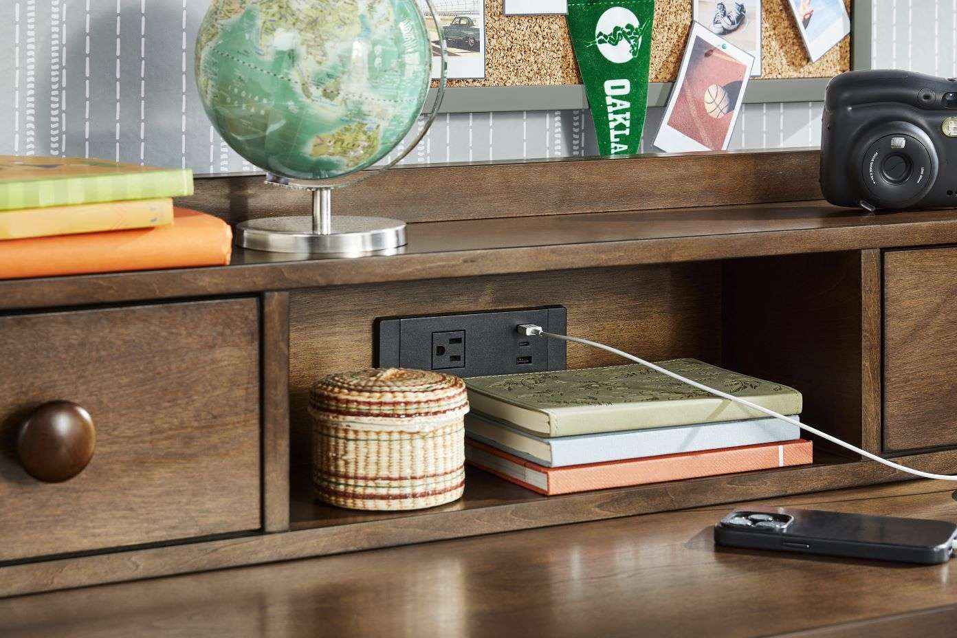 Wooden desk with a globe, books, and a charging station.