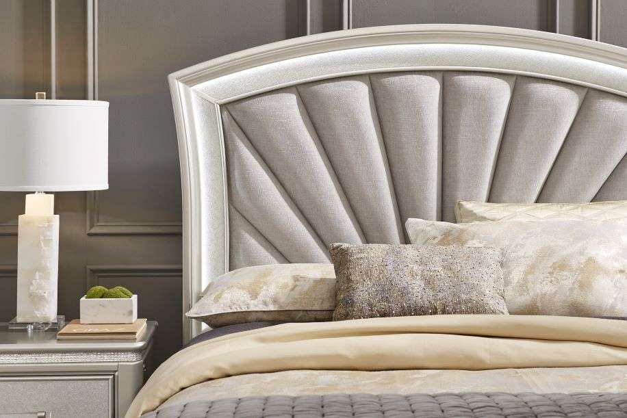 Bed with a fan-shaped headboard, pillows, and a bedside lamp.
