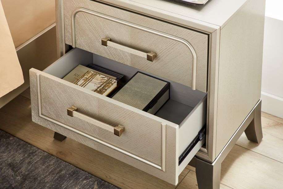 Nightstand with two drawers, one open, containing books and a box.
