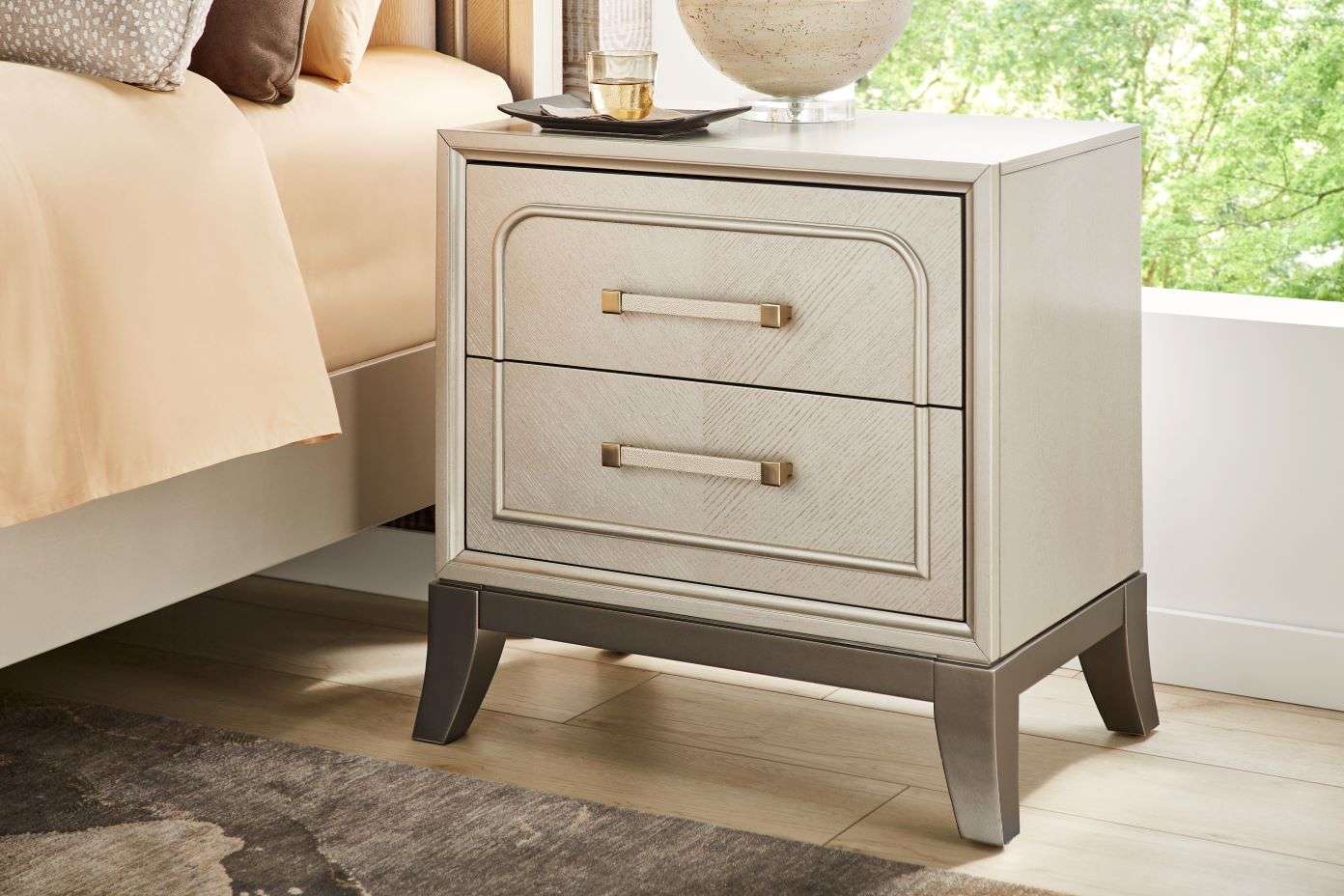Nightstand with two drawers, light wood finish, and metal legs.
