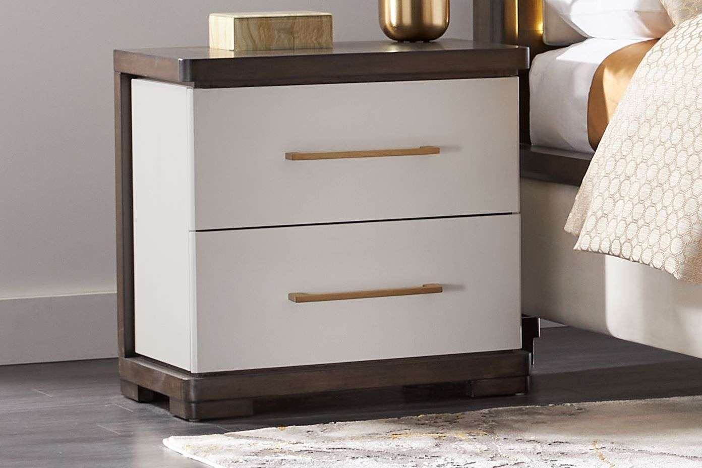 Nightstand with two drawers, gold handles, and a dark wood frame.