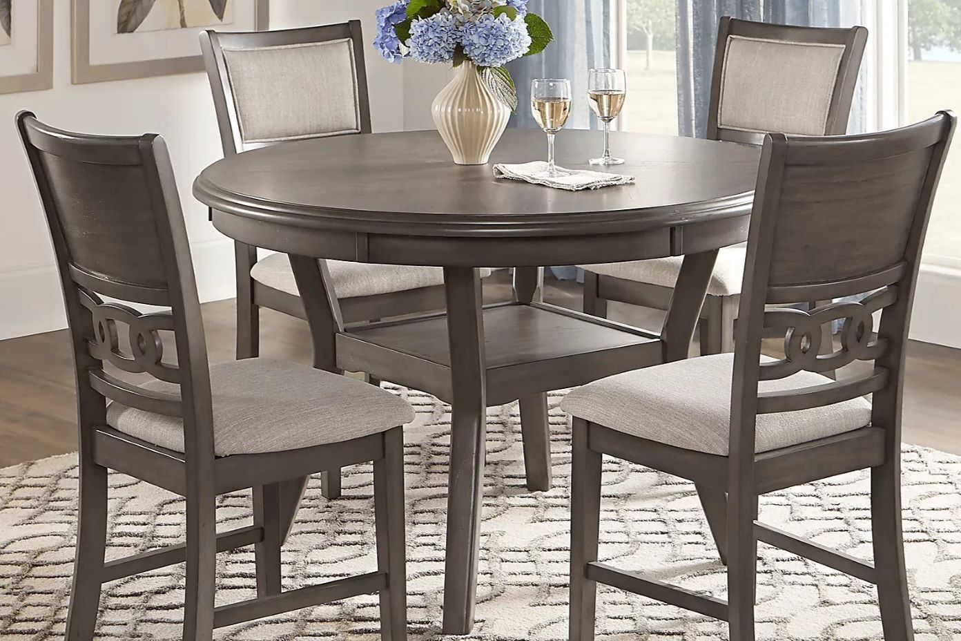 Round dining table with four chairs. The table and chairs are gray.
