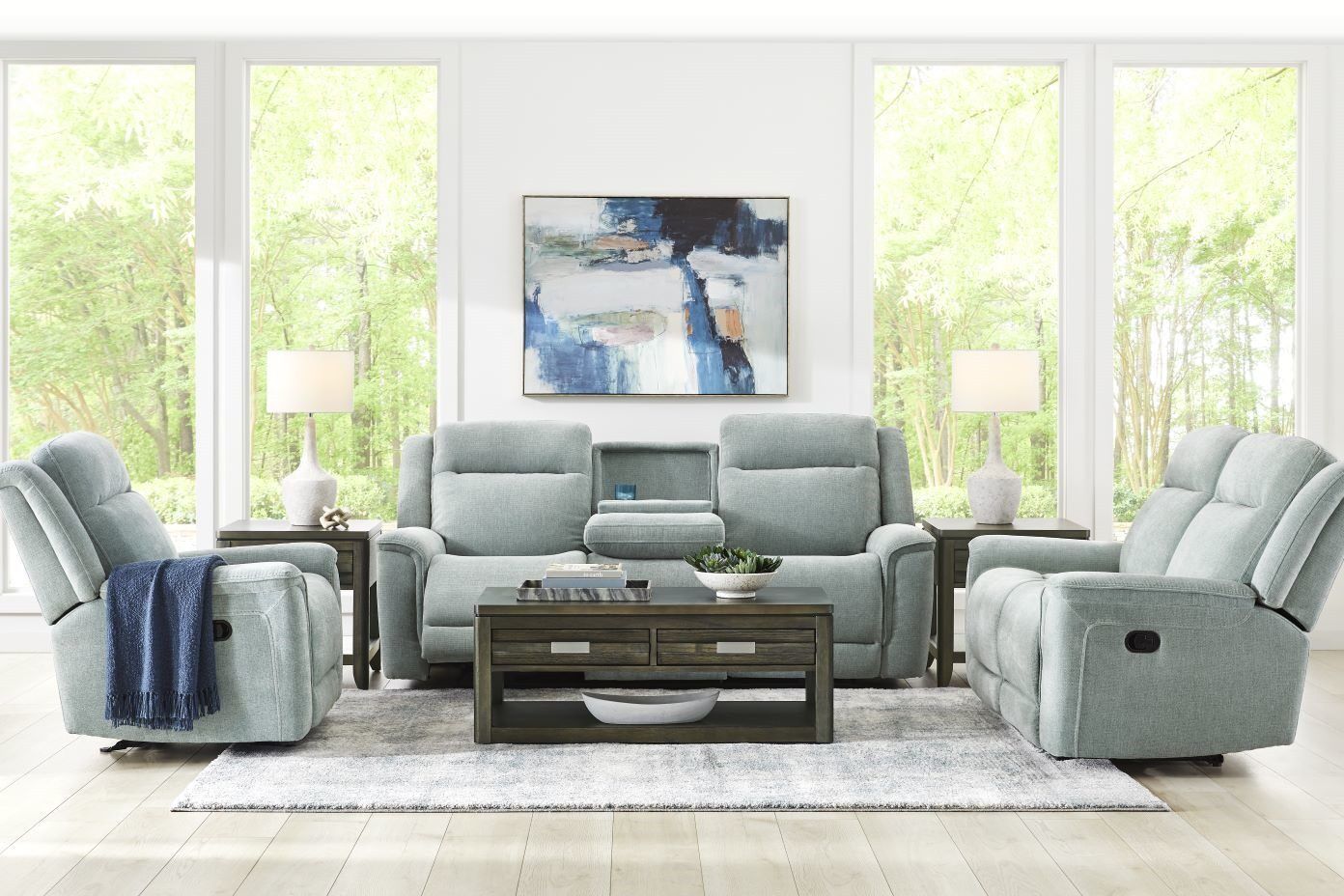Living room furniture set with light blue recliners, a coffee table, and a rug.
