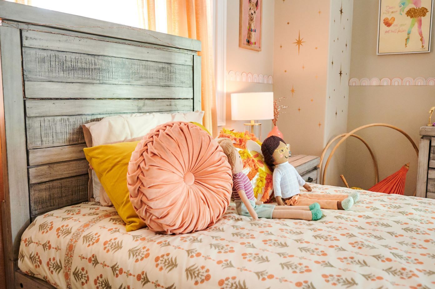 A bed with a wooden headboard, pillows, and dolls.
