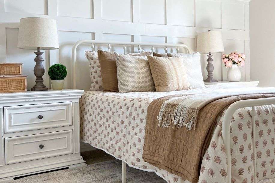 A bedroom with a white bed frame, nightstands, and floral bedding.
