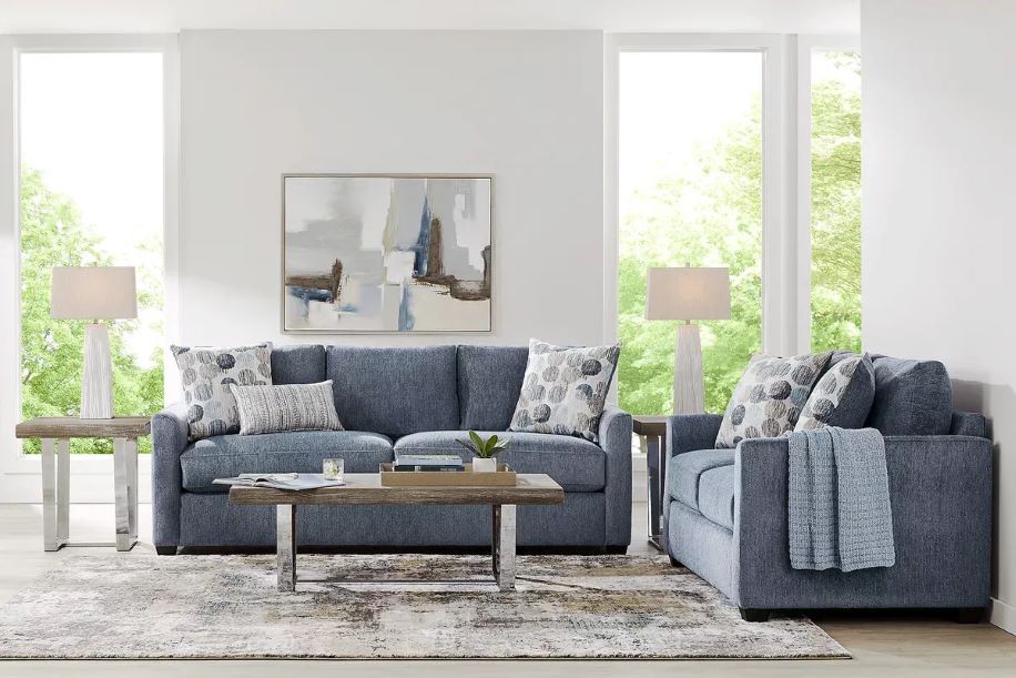 Blue sofa and chair set with patterned pillows, a rug, and a coffee table.
