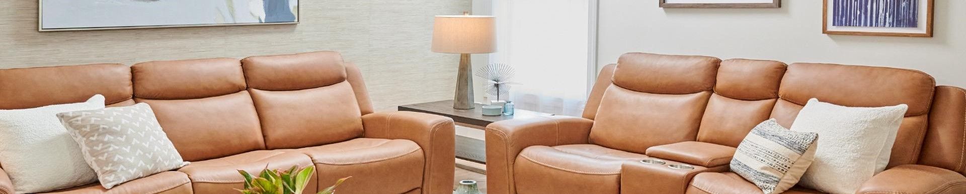 Two brown leather reclining sofas with pillows.
