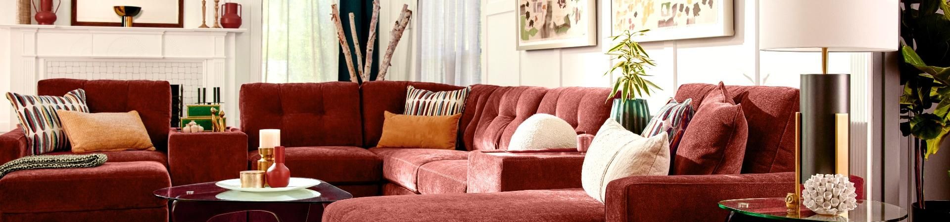A red sectional sofa with decorative pillows and a glass coffee table.
