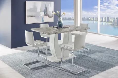 A modern dining set with a marble-look table, white chairs, and a blue rug.
