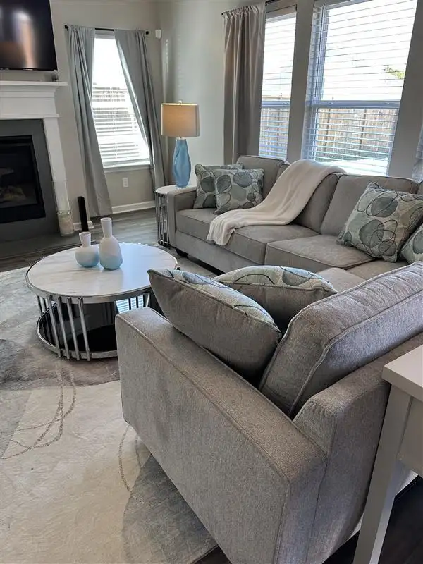 A gray sectional sofa with decorative pillows and a white throw blanket.
