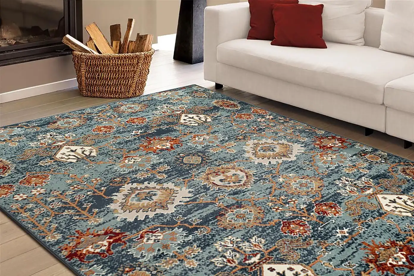 Blue patterned area rug in a living room with a white couch and red pillows.