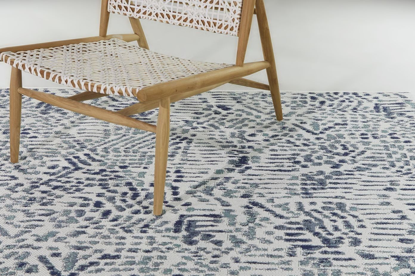 Wooden chair with woven seat and back on a patterned rug.
