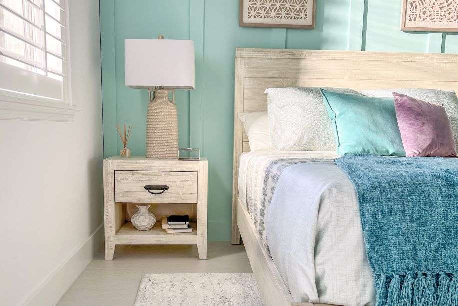 Bedroom with a nightstand, bed, and teal wall.
