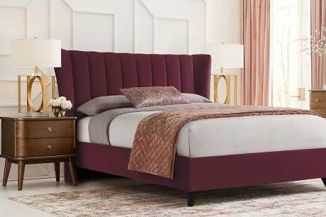 A burgundy upholstered bed with a tall headboard, two nightstands, and lamps.